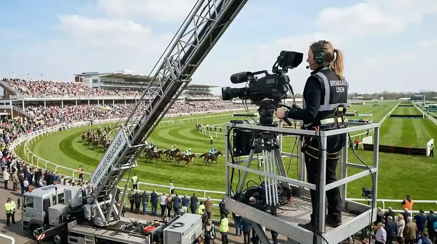 ITV camera crew filming at Aintree with the Grand National course behind them